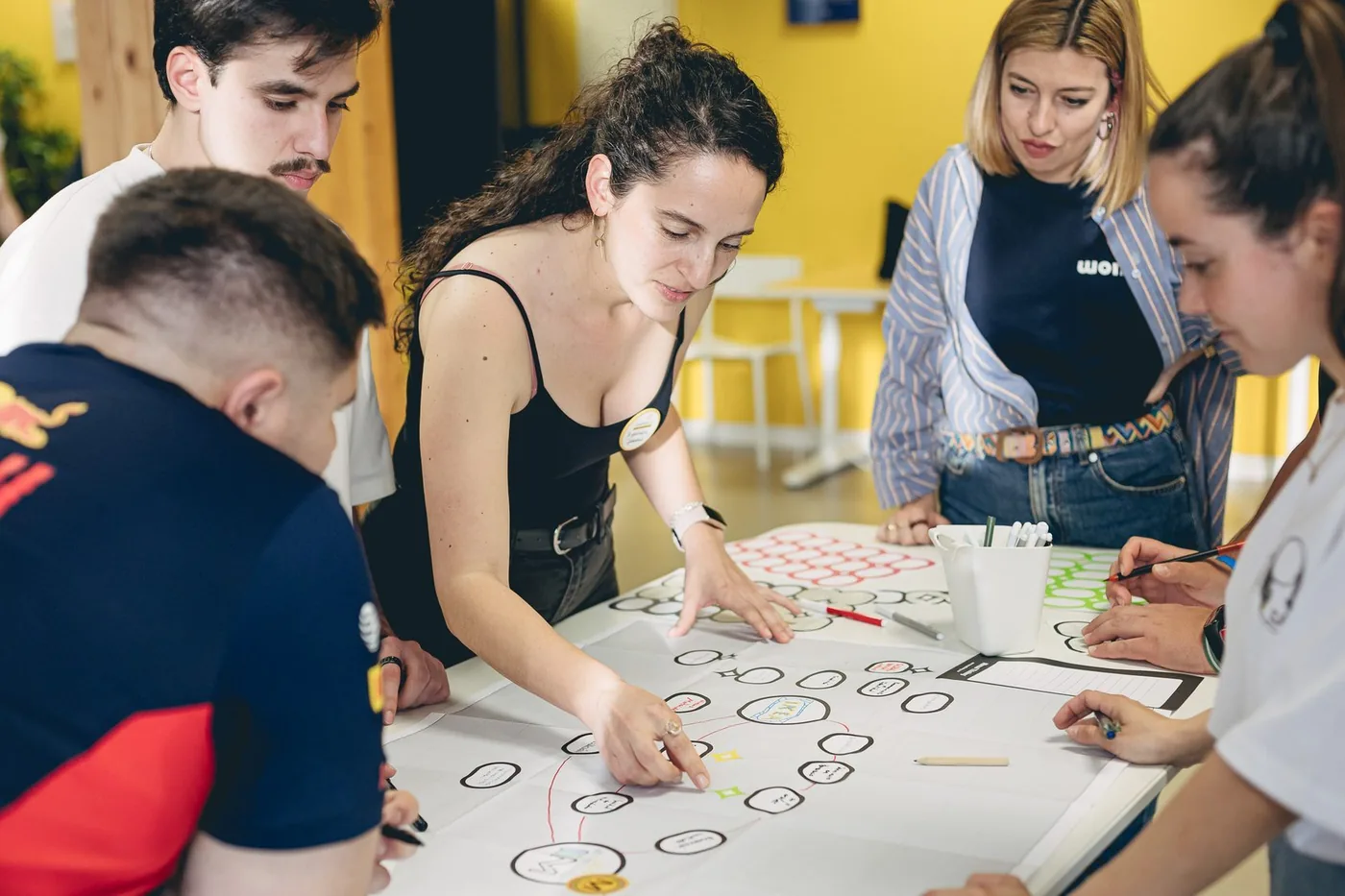 Participantes de CreativeLab trabajando juntos sobre un esquema dibujado en una mesa