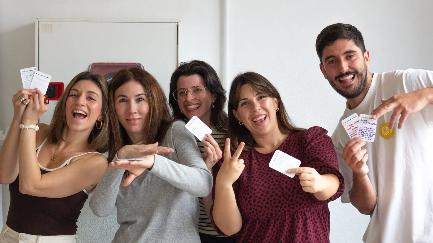 Grupo de participantes sonriendo y mostrando tarjetas al final de una sesión