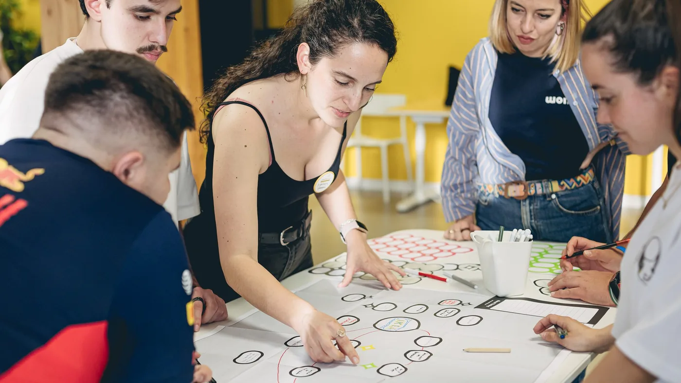 Participantes de CreativeLab trabajando juntos sobre un esquema dibujado en una mesa
