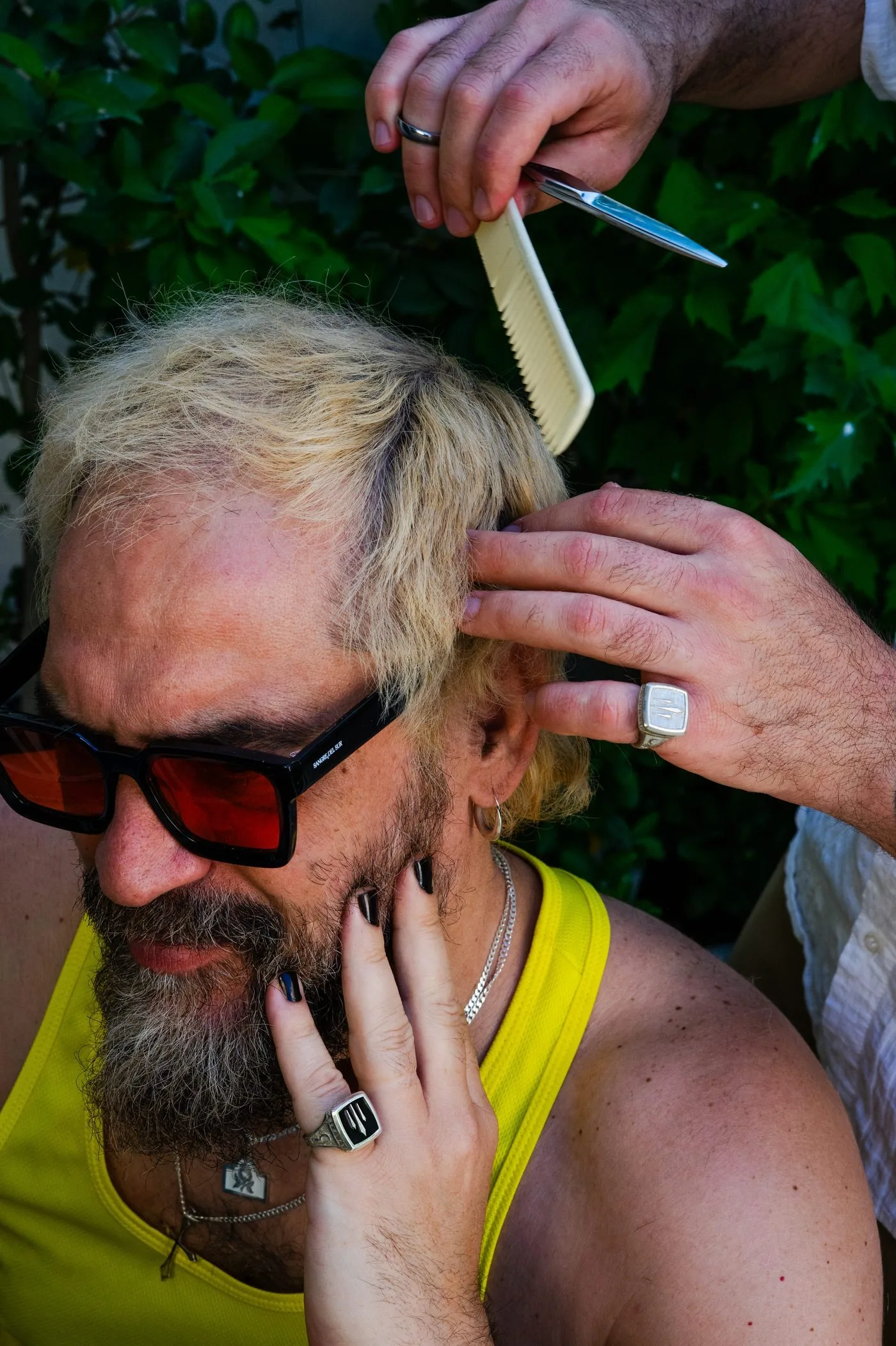 Retrato de un hombre con gafas de sol rojas mientras le cortan el pelo, para la identidad de Sangre del Sur