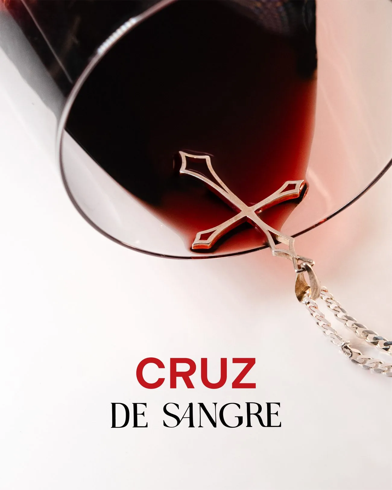 Publicación «Cruz de Sangre» con un colgante de cruz dentro de una copa de vino tinto