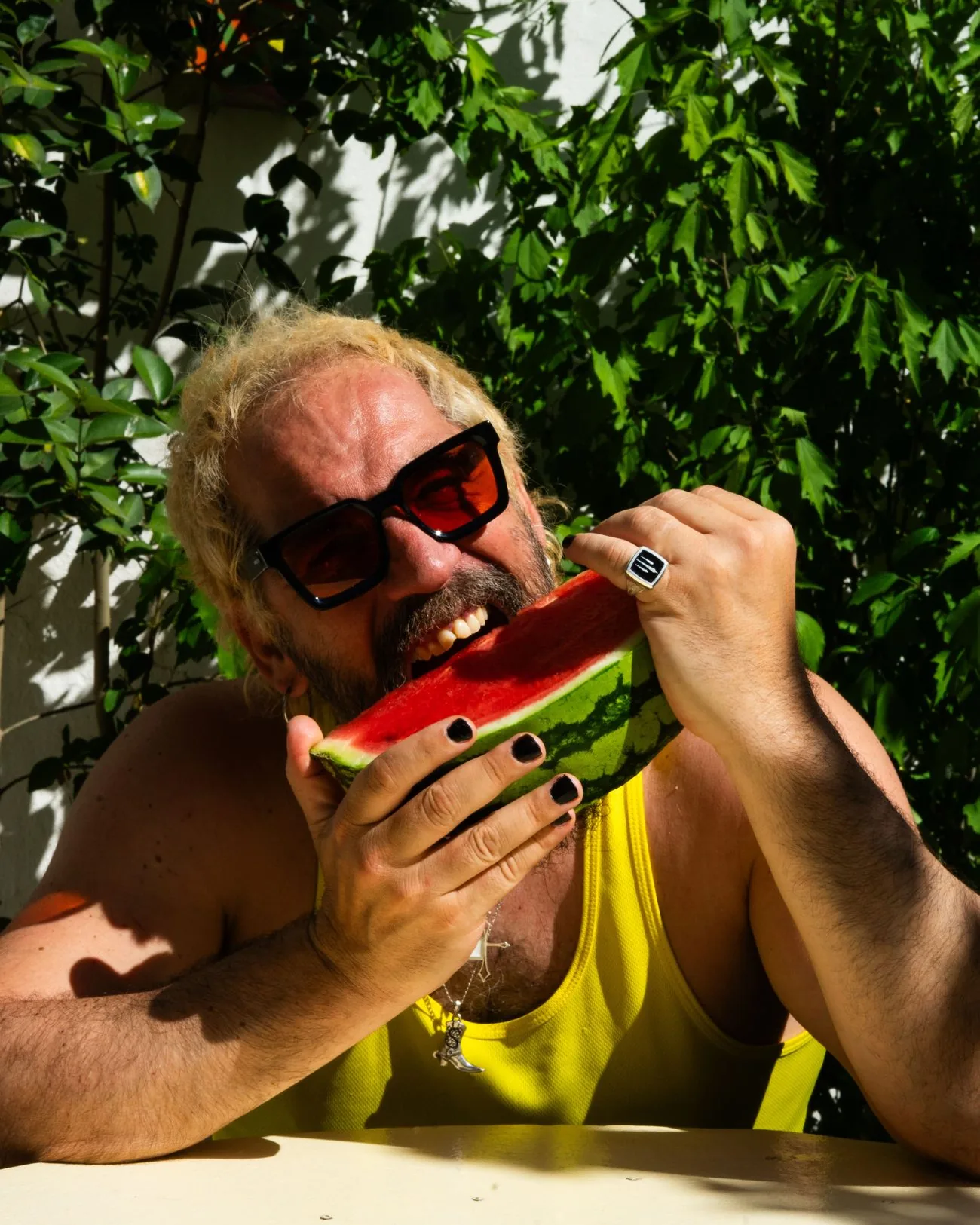 Tony Moreno con gafas de sol rojas dando un mordisco a una tajada de sandía